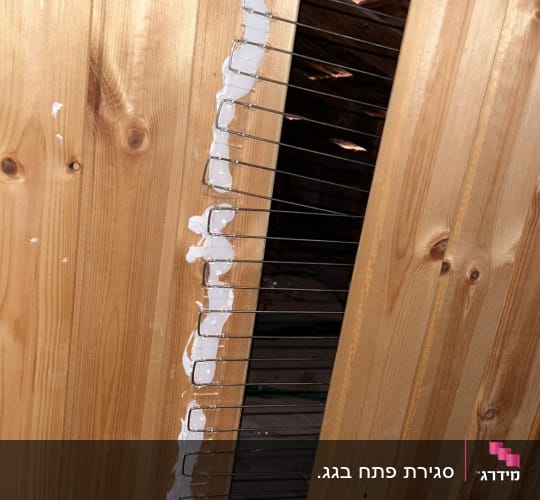 רשת מתכת מותקנת על קיר עץ עם חומר איטום